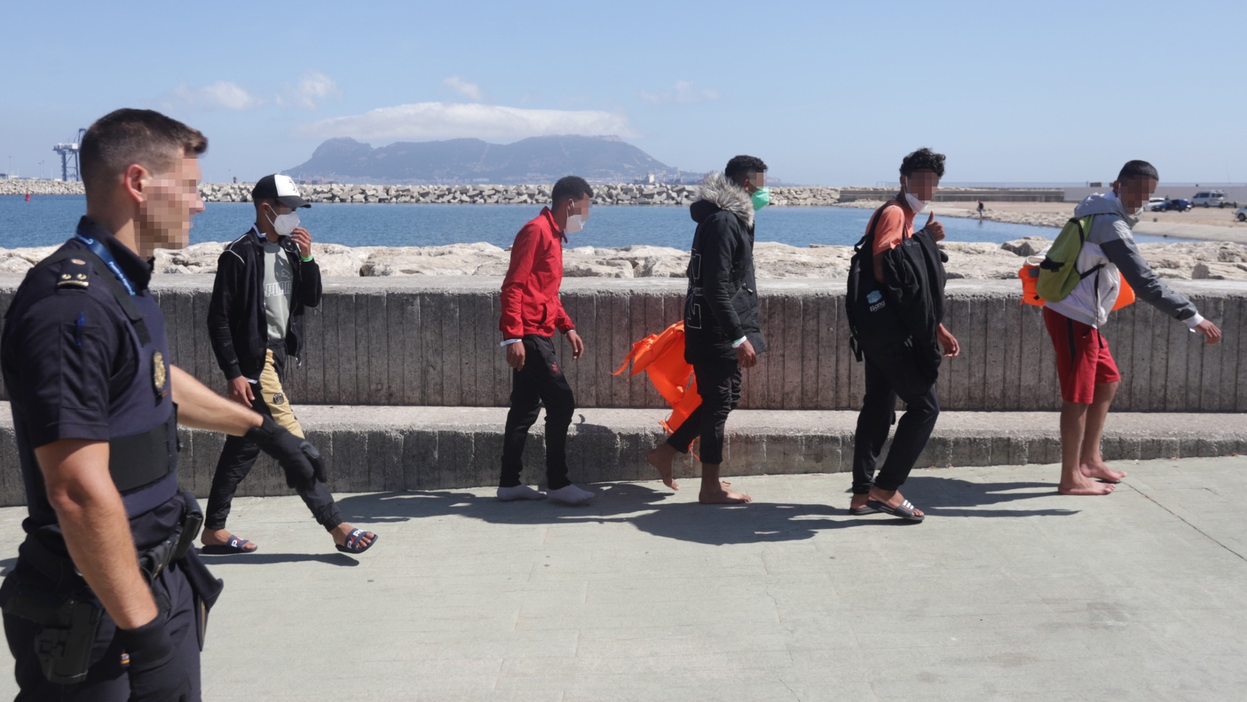 Inmigrantes magrebíes interceptados en aguas de Barbate (Cádiz) caminan junto a un policía nacional (NONO RICO).