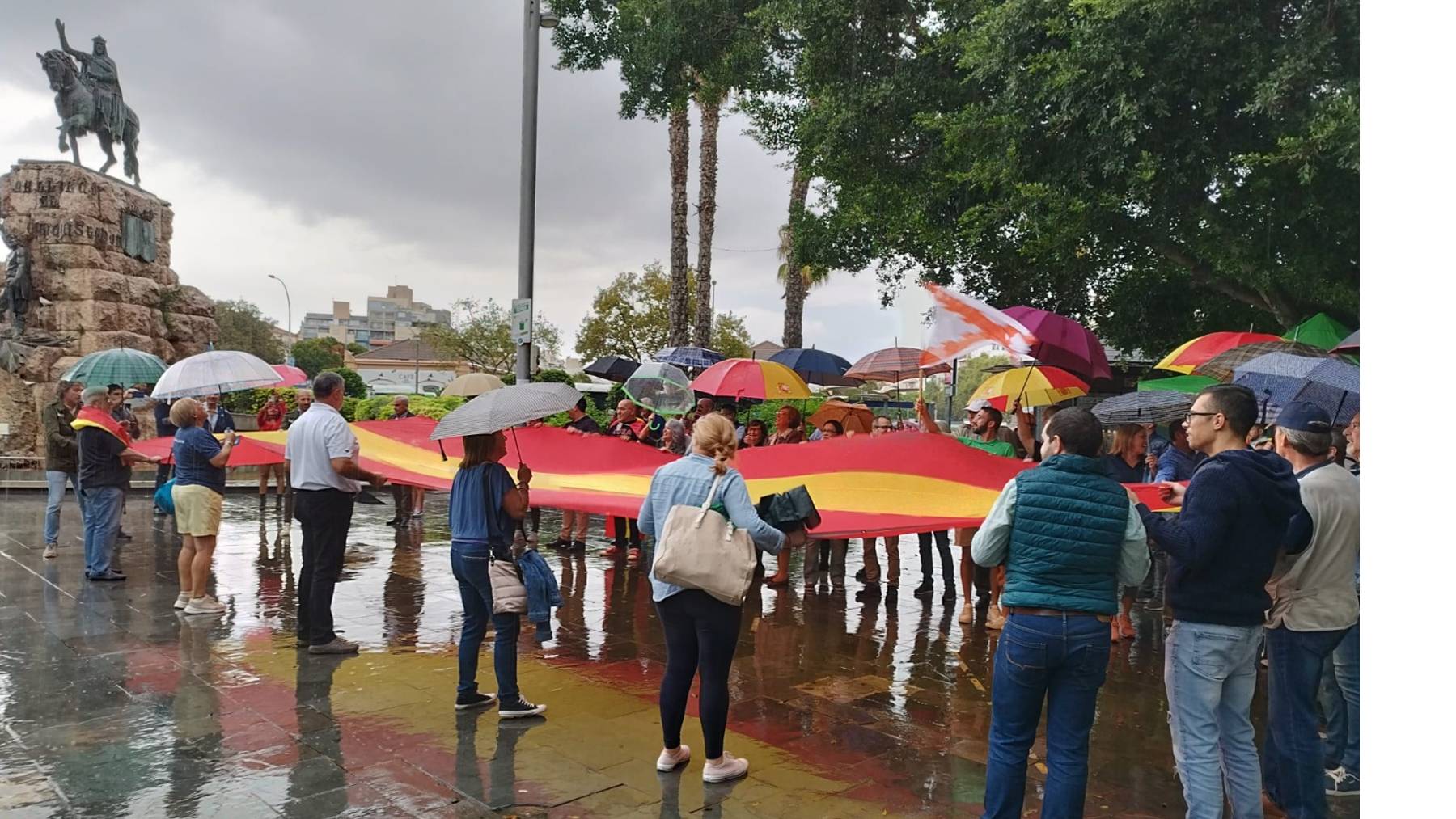 Dirigentes y simpatizantes de Vox despliegan la bandera española en la Plaza de España.