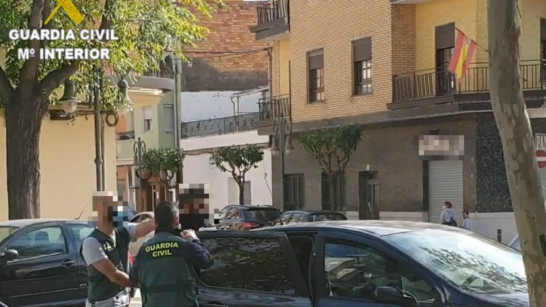 Dos agentes de la Guardia Civil introducen en el vehículo a uno de los detenidos.