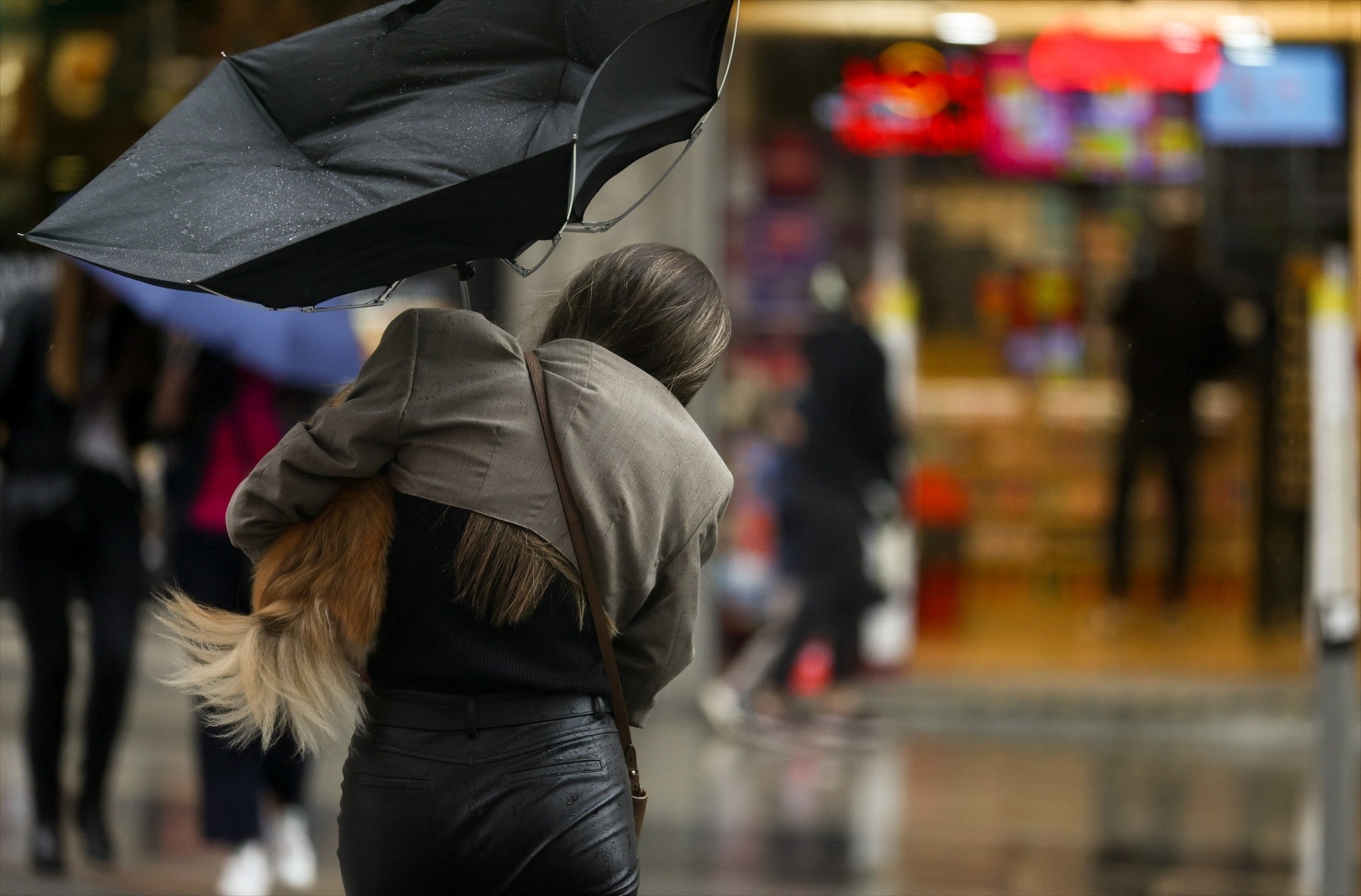 Una mujer se protege de la lluvia con un paraguas (EP)