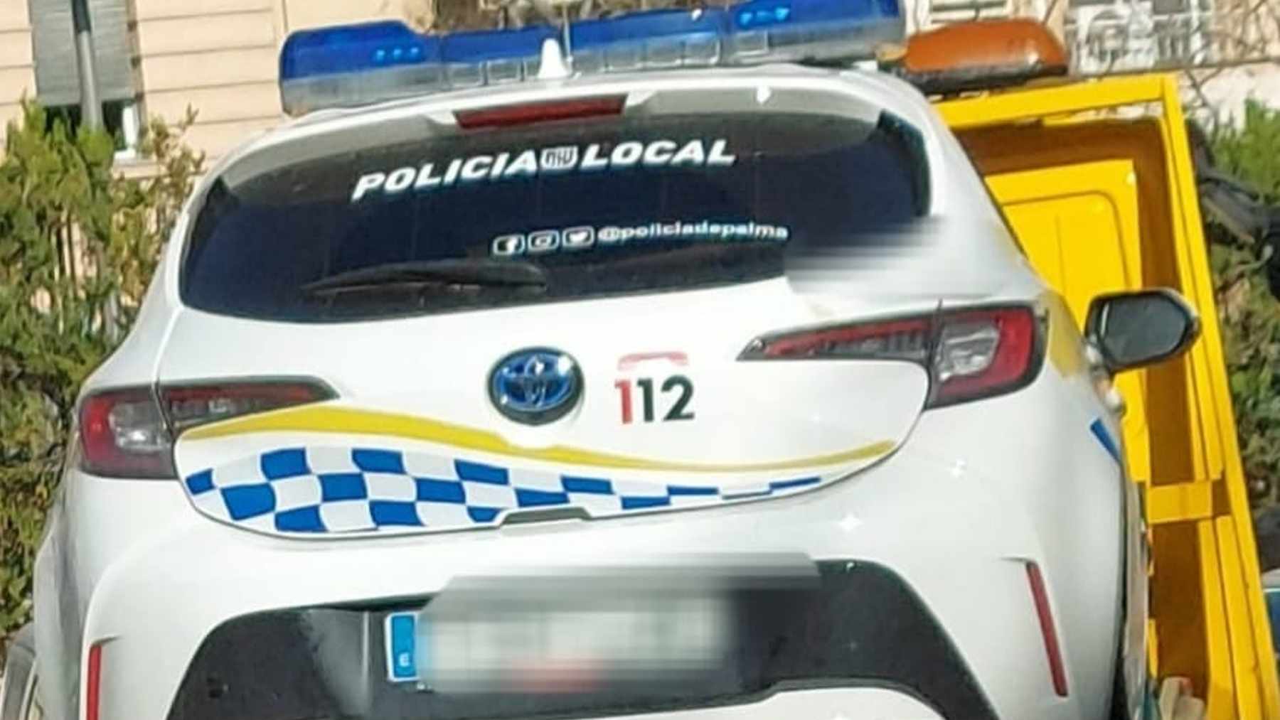 Una grúa transporta un coche de la Policía Local de Palma averiado.