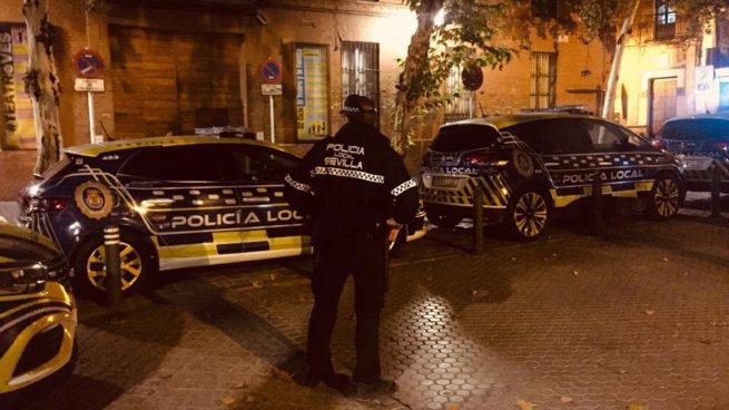 Un agente de la Policía Local de Sevilla vigilando los coches patrulla (CSIF).