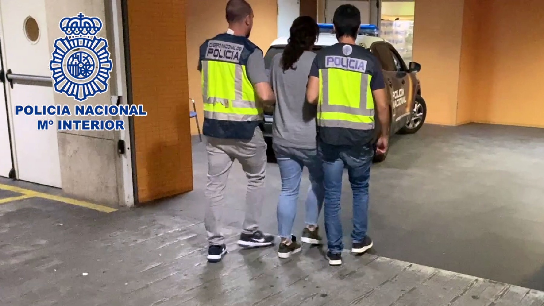 La detenida es custodiada por 2 agentes de la Policía Nacional.