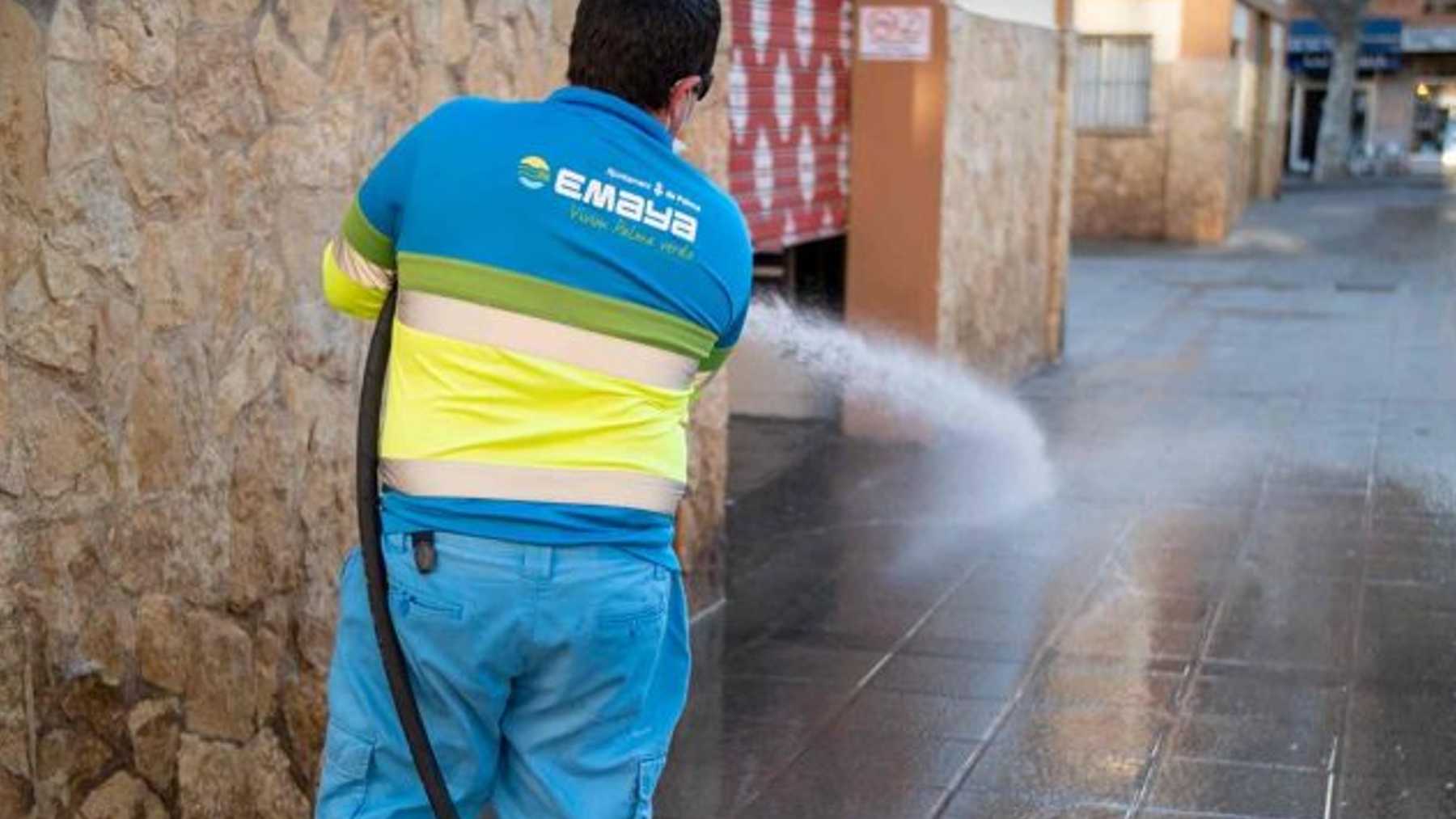 Un operario de la empresa municipal Emaya limpia con agua una plaza de Palma.