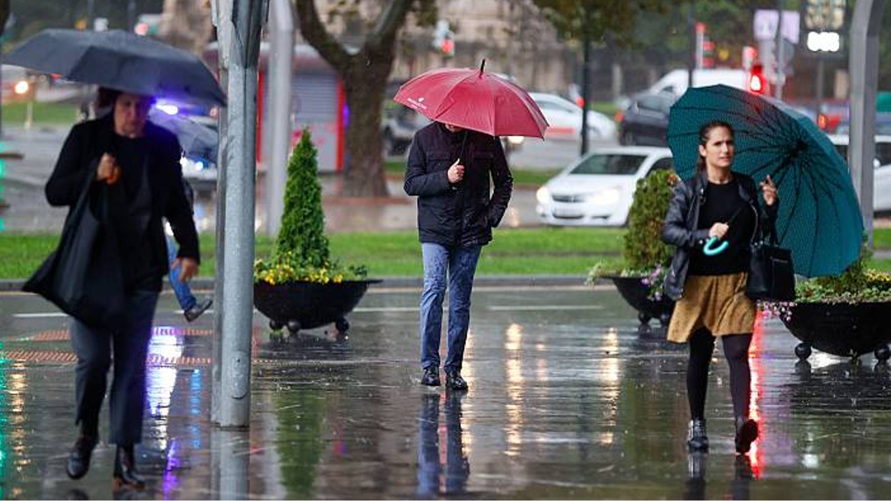 Ciudadanos refugiándose de la lluvia en la Plaza de España de Palma.