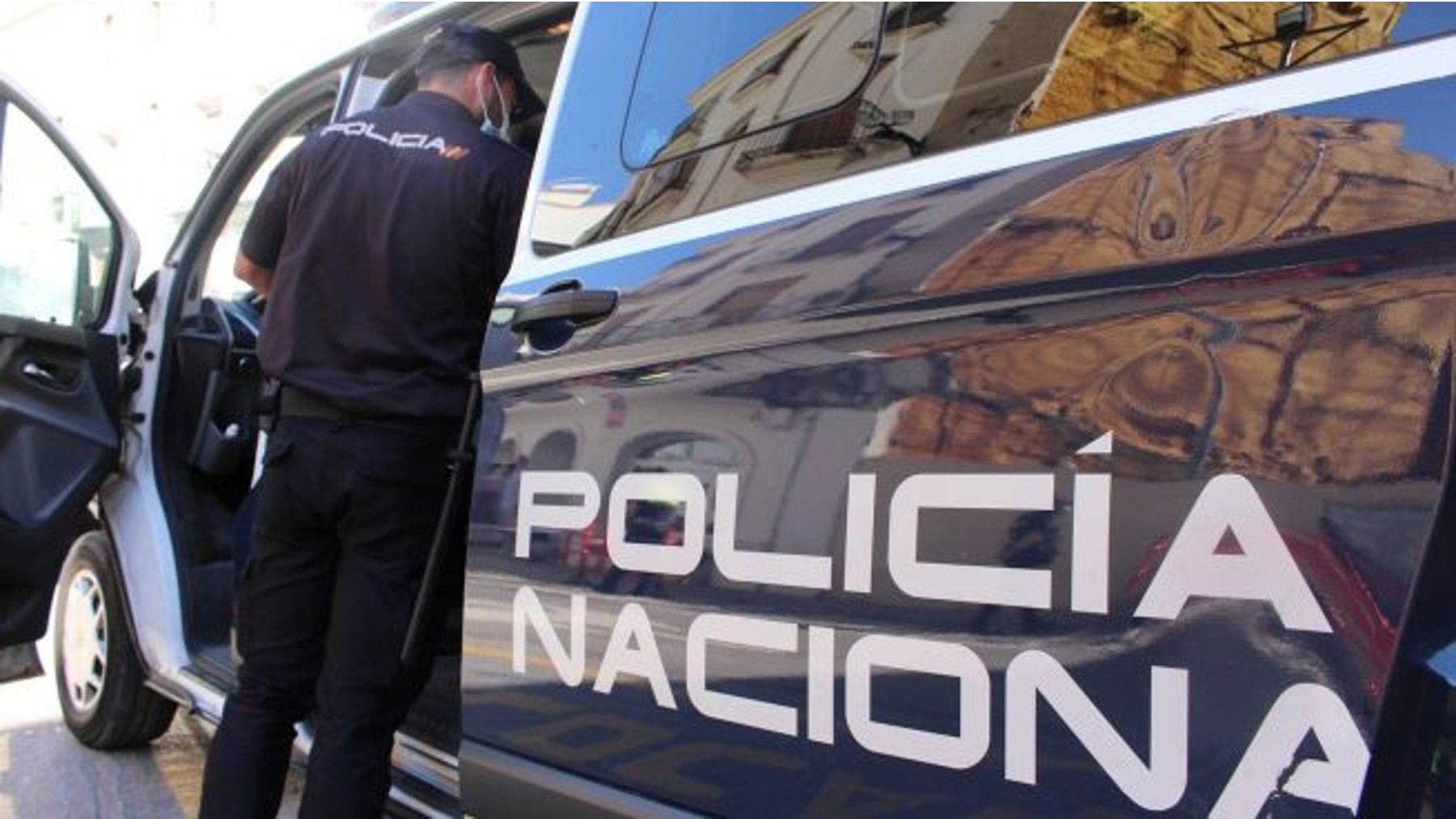 Un agente de la Policía Nacional junto al coche patrulla.