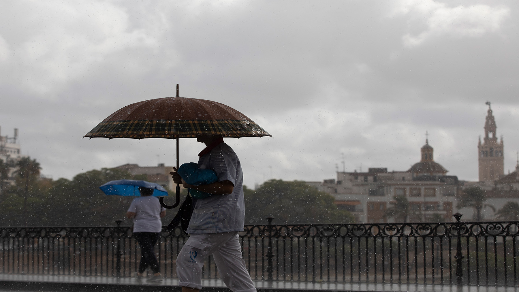 Dos personas caminan bajo la lluvia en Sevilla (Foto: EP)
