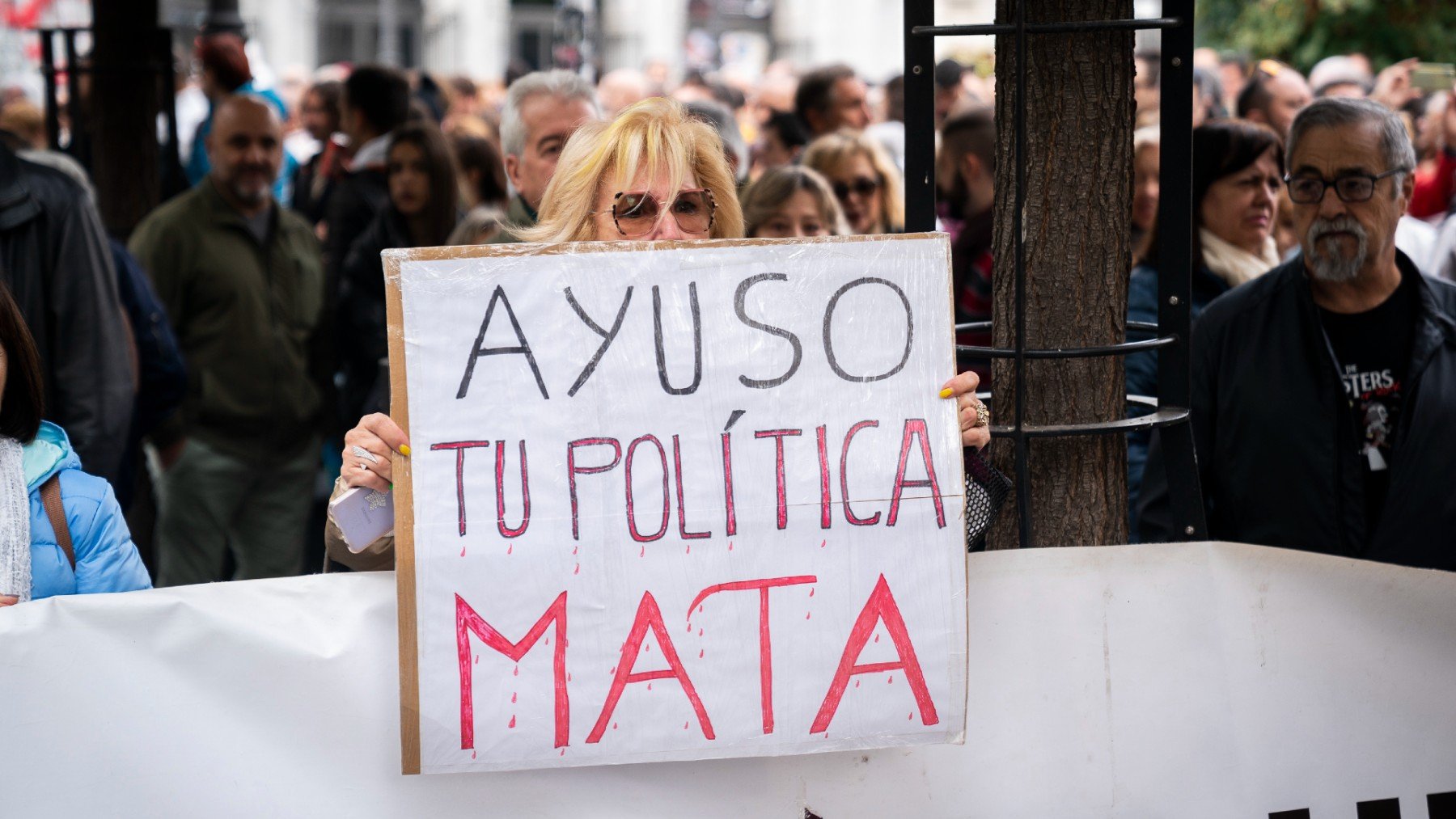 Una manifestante porta un cartel contra Ayuso en la protesta por la sanidad.