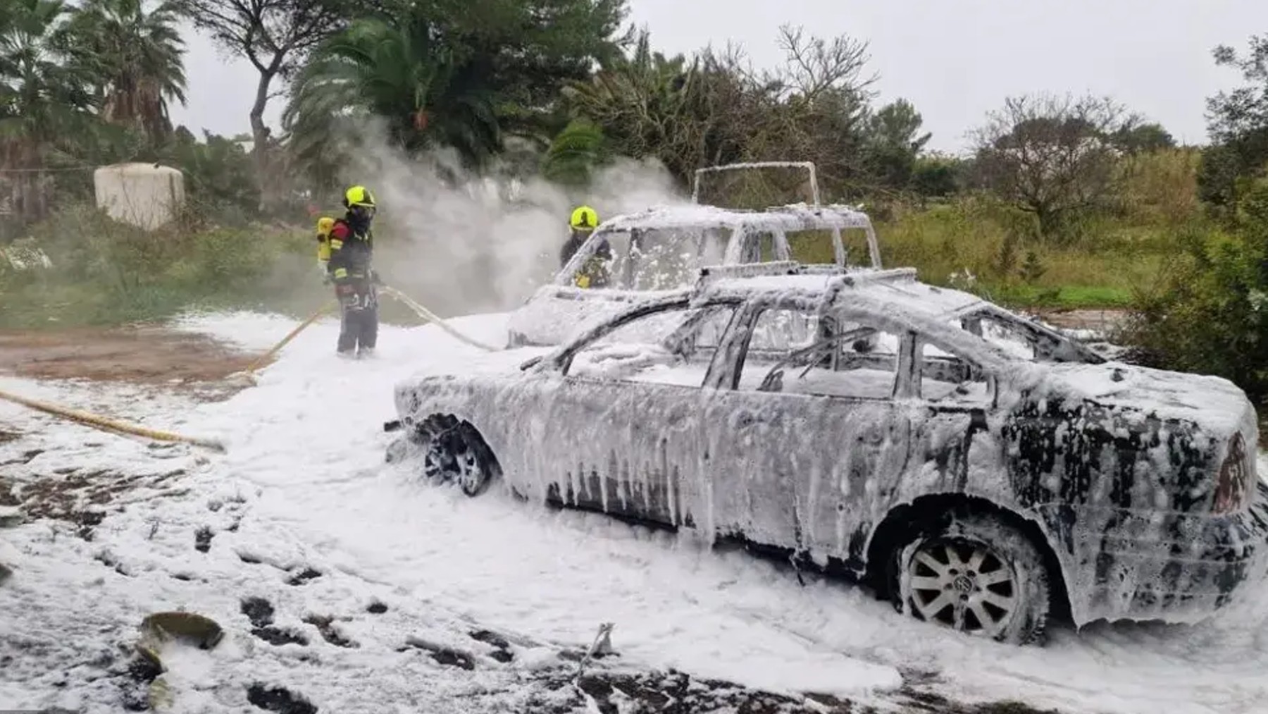 Bomberos del Consell de Formentera apagando el fuego en los coches.