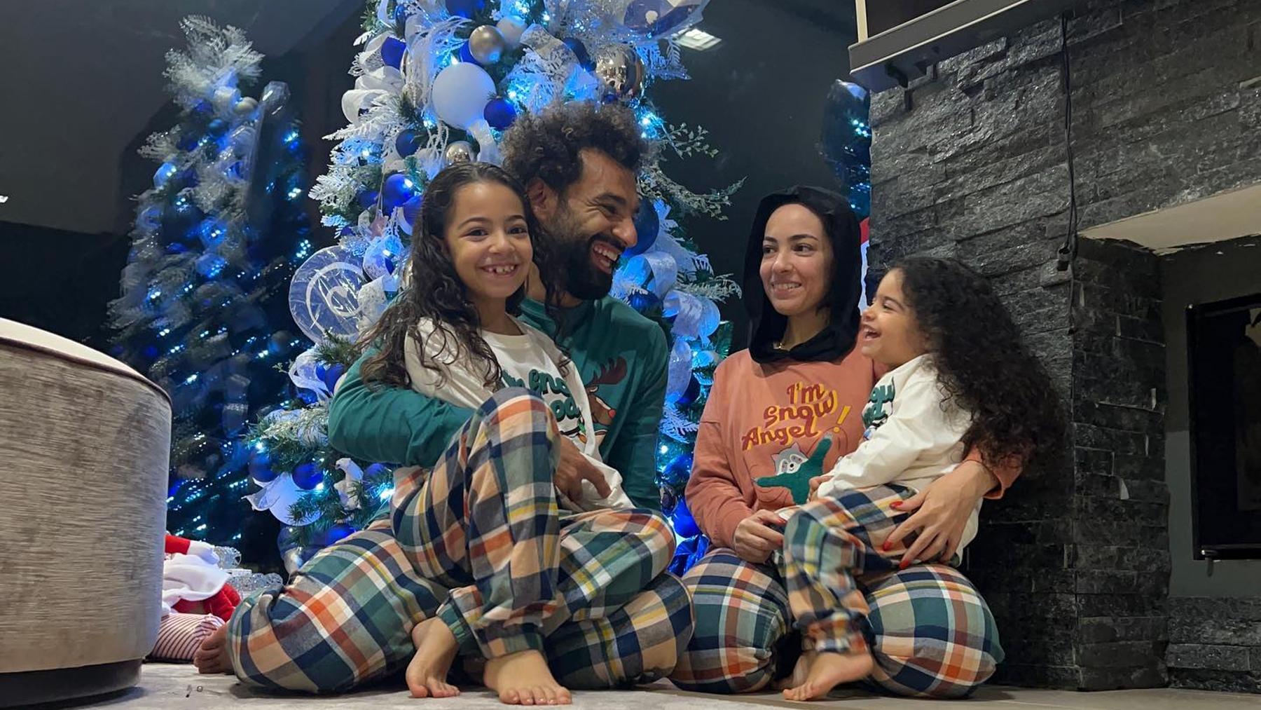 Salah posa junto a su familia delante de un árbol de Navidad.