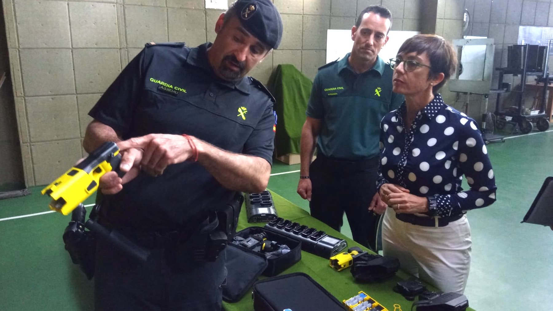 La directora de la Guardia Civil observa una pistola eléctrica.