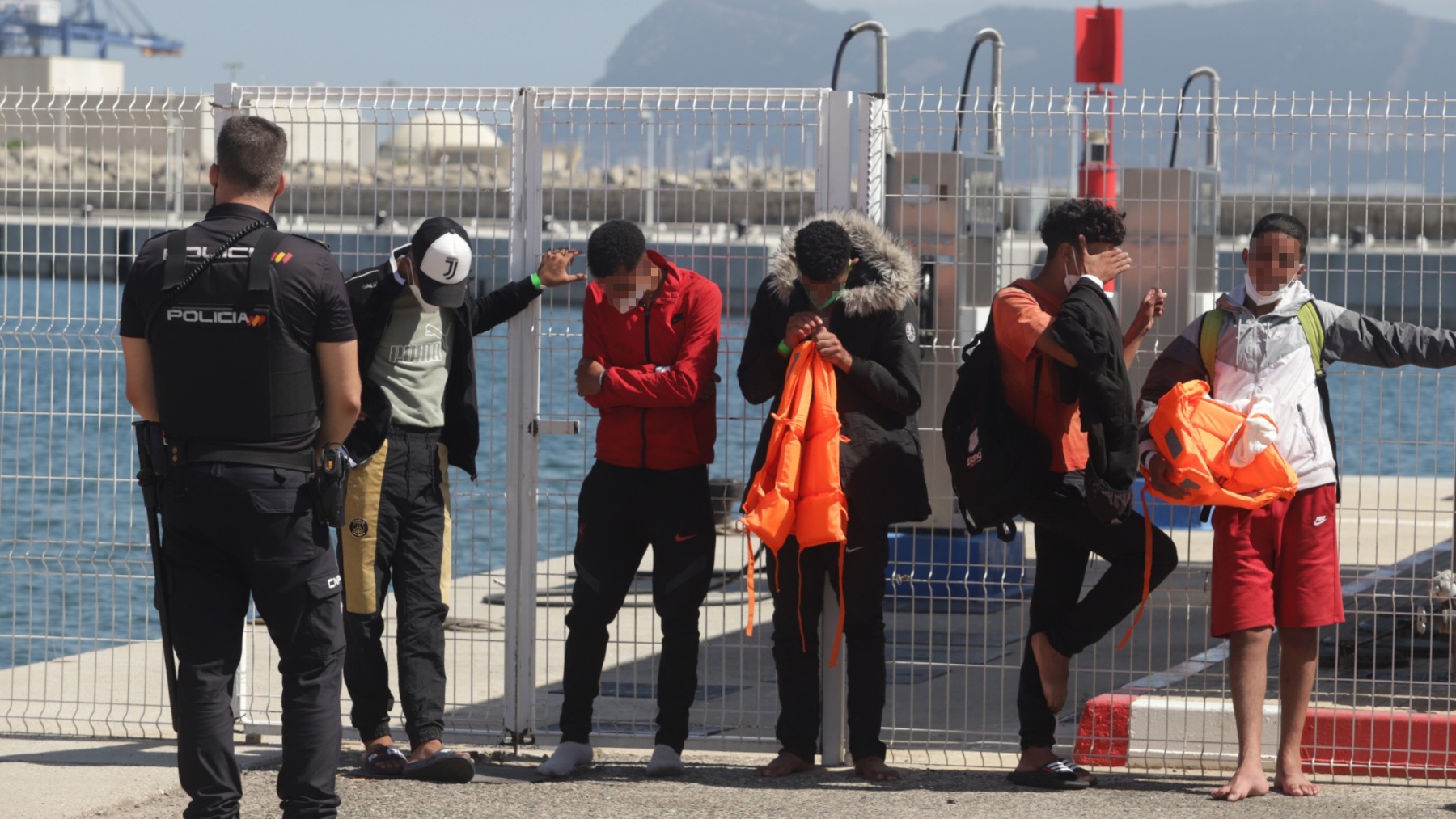 Un policía nacional custodia a cinco menores magrebíes llegados en patera a Barbate, Cádiz (NONO RICO).