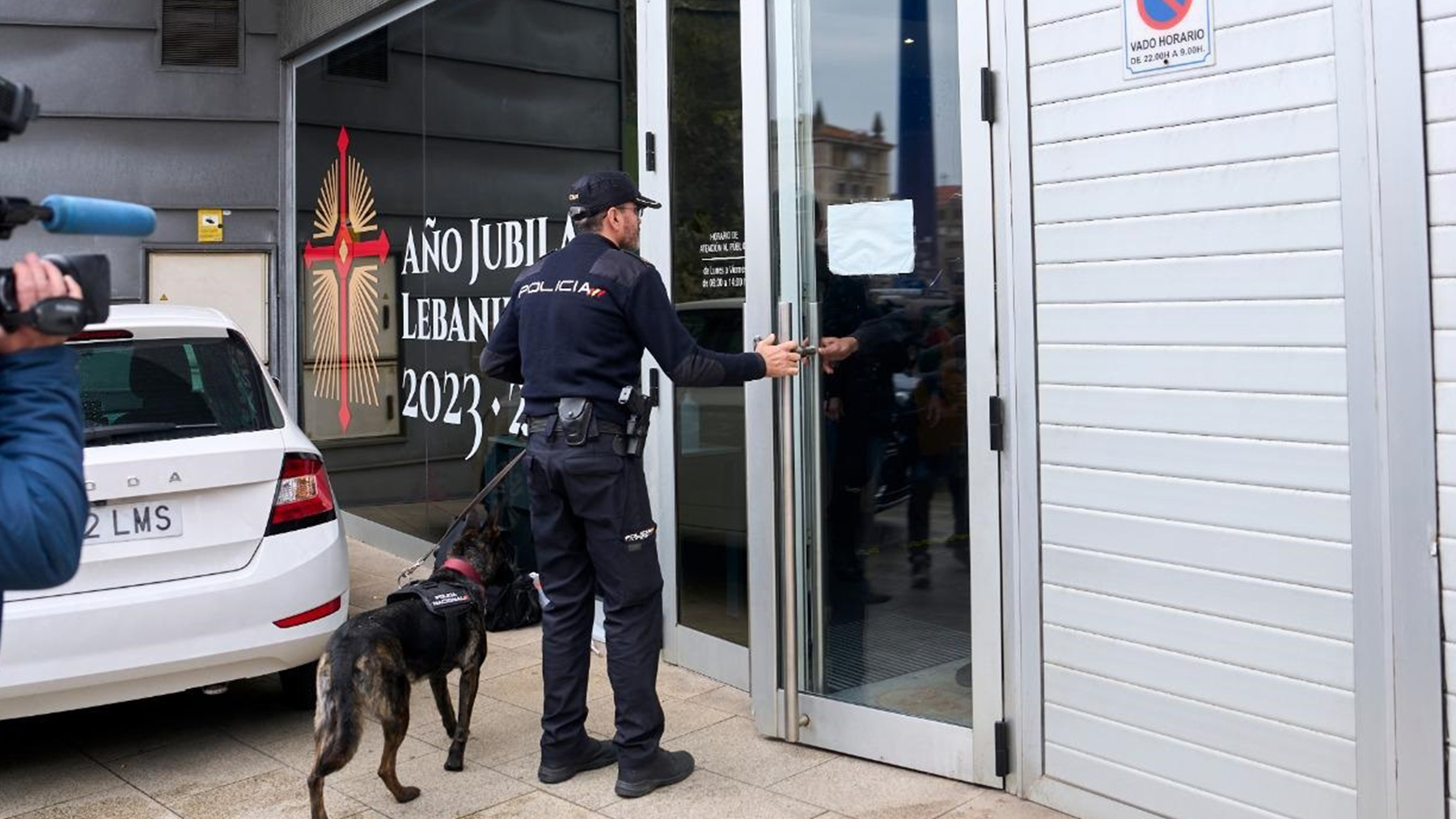 Un agente entra con un perro en la sede de la Consejería de Obras Públicas de Cantabria.