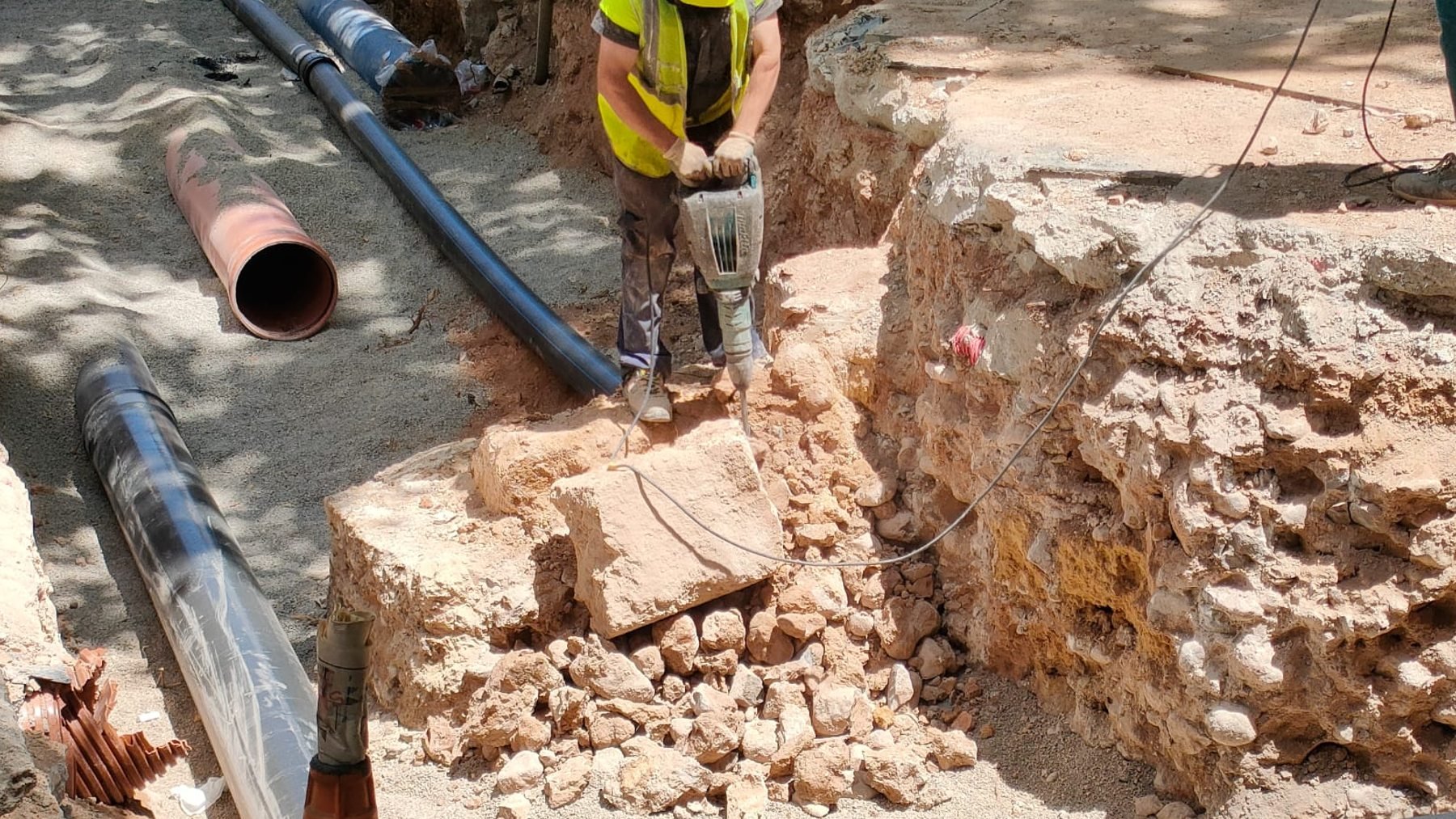 Un obrero taladrando un resto de la antigua muralla para hacer paso a una canalización.