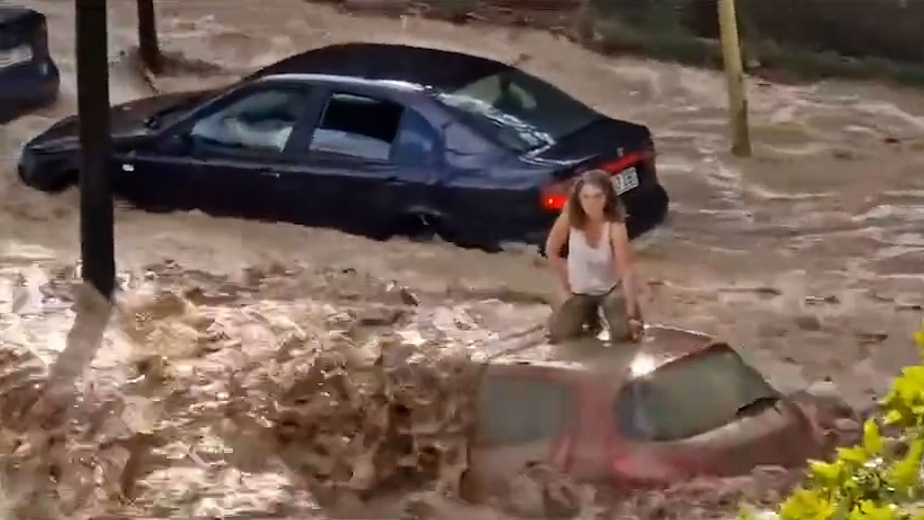 Una mujer en el techo de su coche durante la riada en Zaragoza
