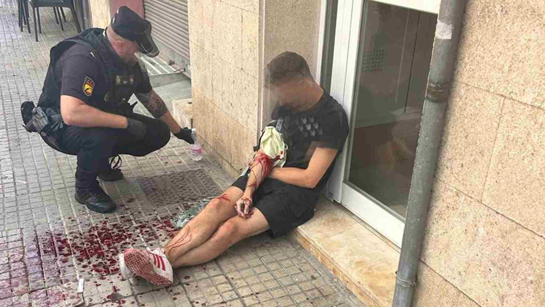 Un agente junto al herido al que le realizó un torniquete. POLICÍA NACIONAL