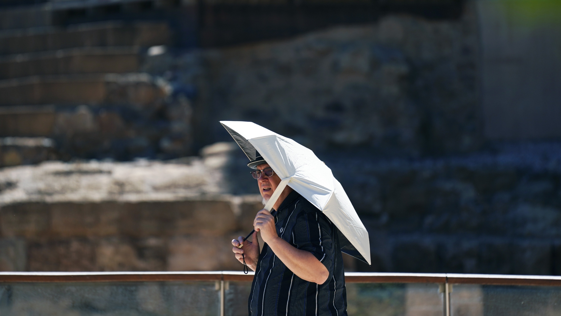 Un ciudadano se protege del calor con un paraguas.