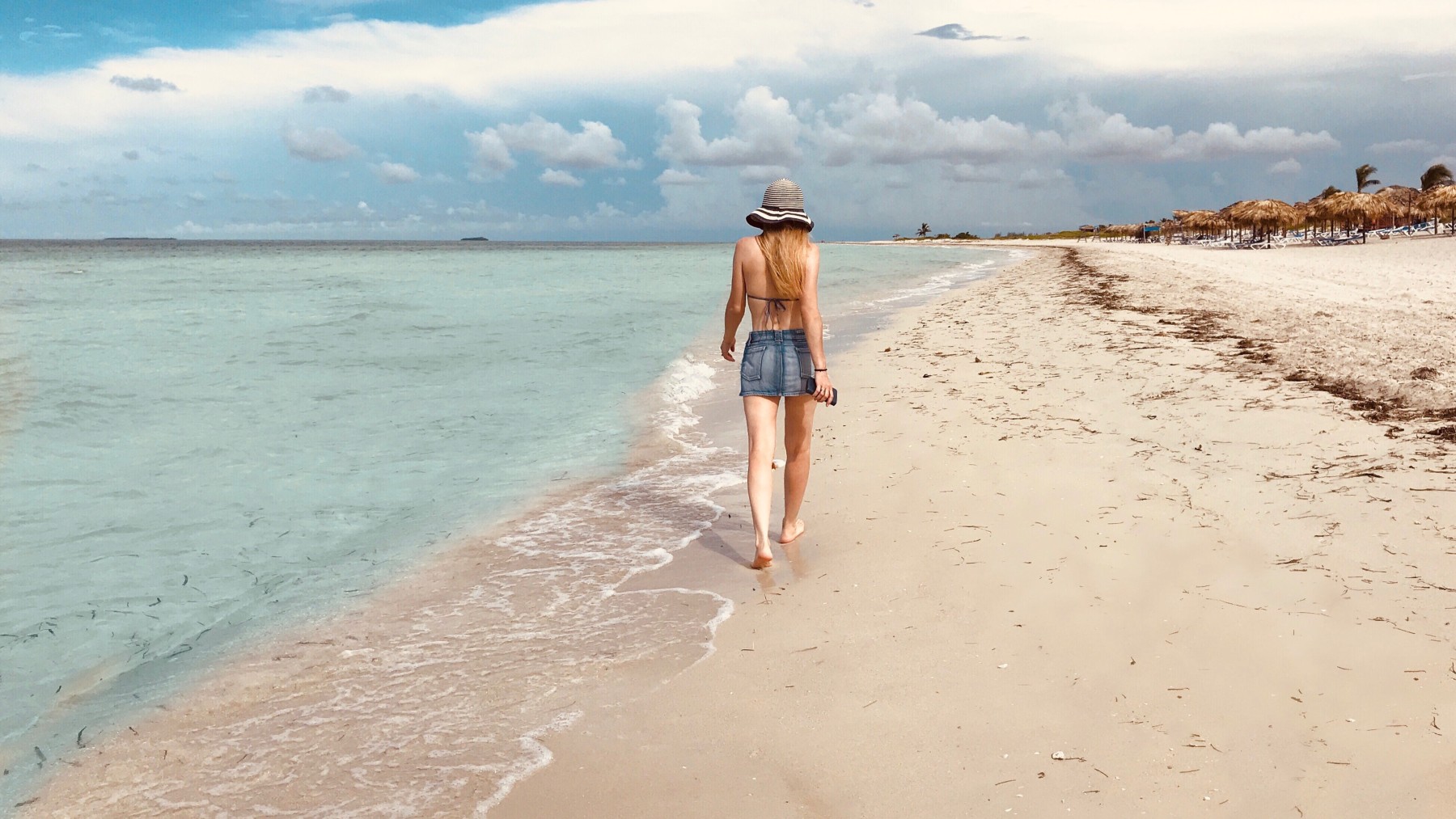 Una mujer camina por la playa.