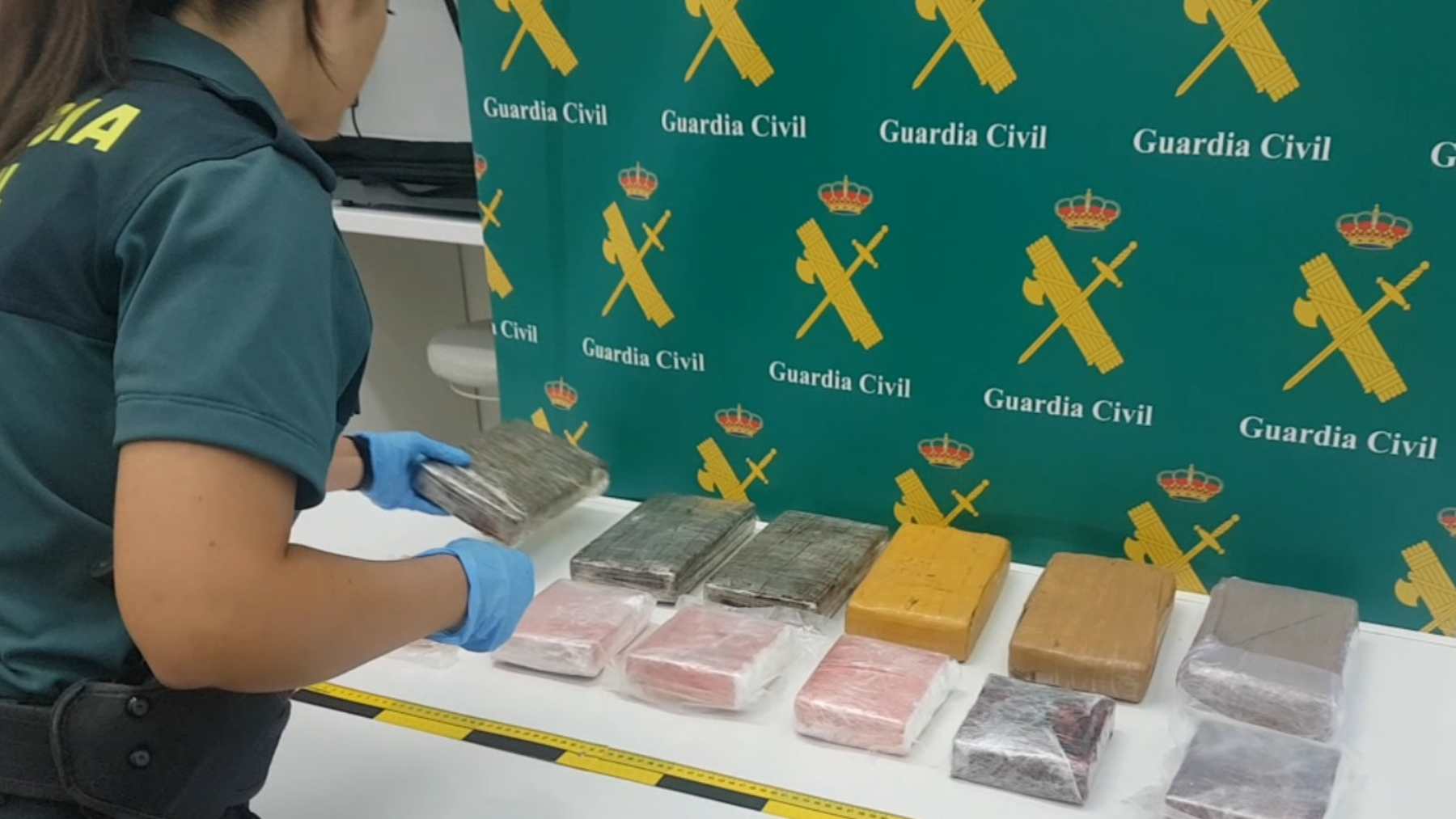 Una agente de la Guardia Civil colocando los 12 paquetes de cocaína incautados en Palma. GUARDIA CIVIL