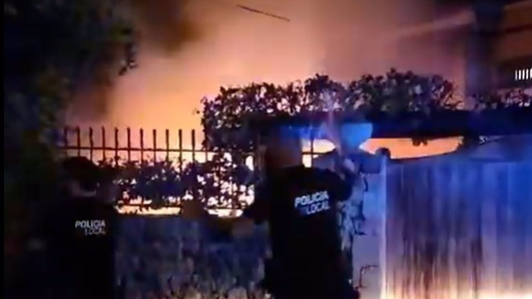 Agentes de la Policía Local de Alcúdia intentan sofocar las llamas con unas mangueras.