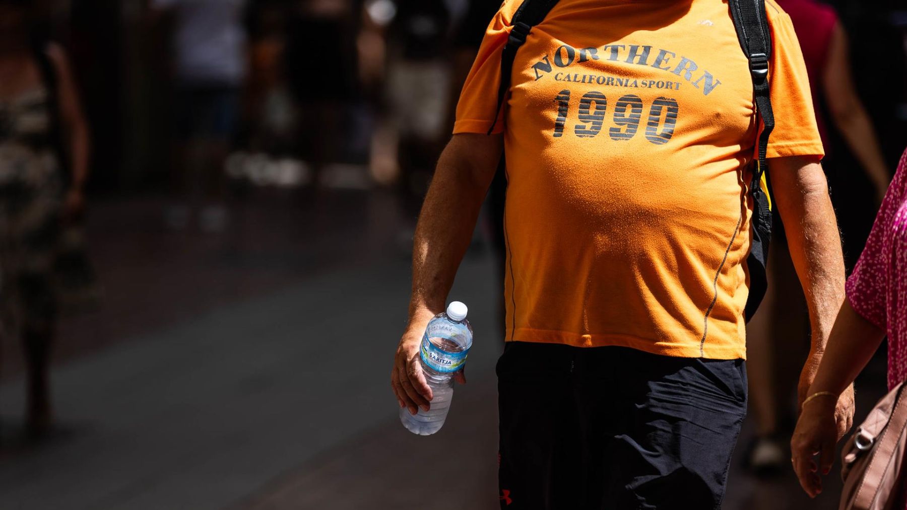 Un hombre con una botella paseando por Palma de Mallorca.