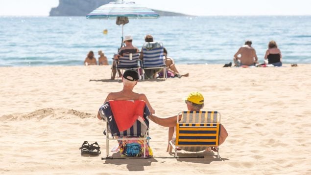 Varias personas toman el sol en la playa.