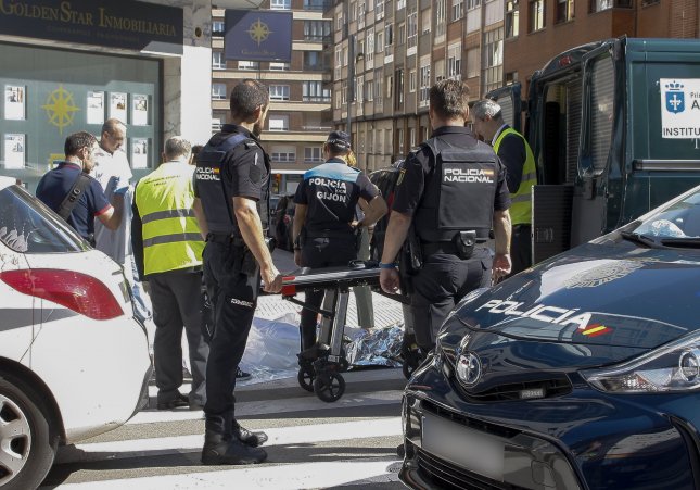 El cadáver de la víctima yace la tarde del miércoles ante su negocio en Gijón