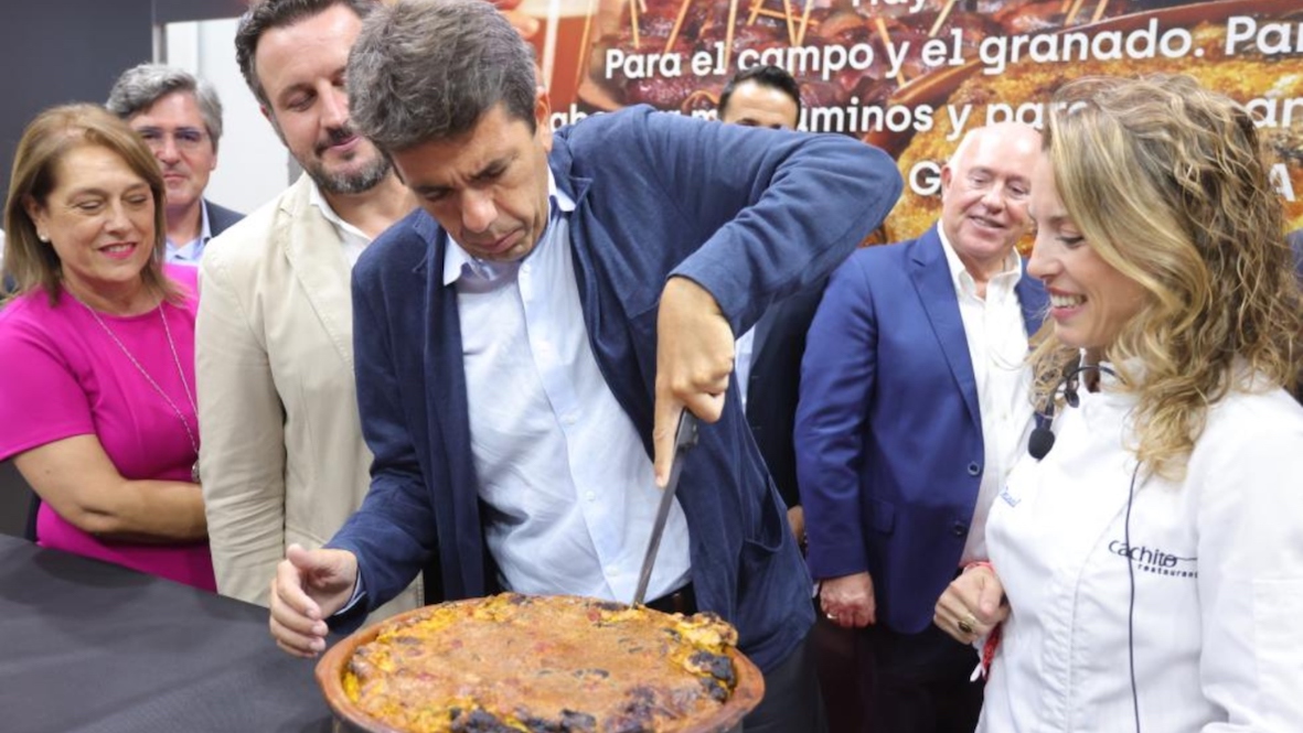 Mazón corta un arroz con costra en ‘Alicante Gastronómica’ ante la mirada del alcalde de Elche Pablo Ruz, este viernes.