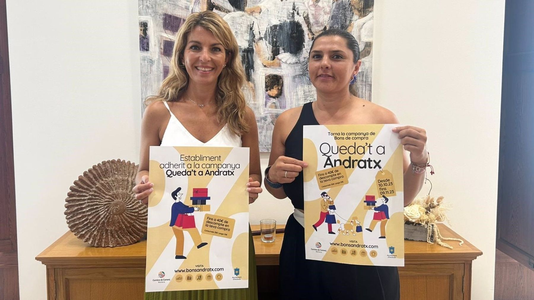 La alcaldesa de Andratx, Estefania Gonzalvo, junto a la regidora de Promoción Económica, Sandra Milena, con los carteles de la nueva edición de la campaña ‘Queda’t a Andratx’