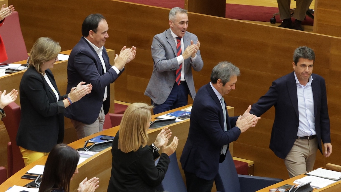 Carlos Mazón recibe el aplauso de su Gobierno y de diputados del PP al regresar al escaño tras su intervención, este miércoles, en las Cortes Valencianas.