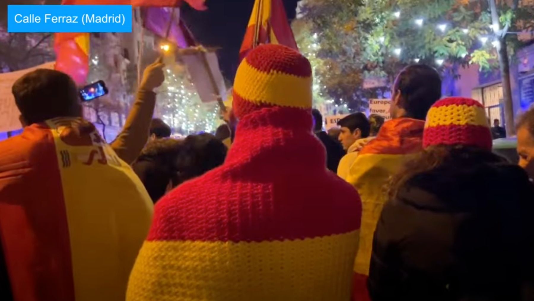 Manifestantes en Ferraz con gorros y mantas de la bandera de España.