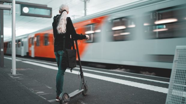 Patinete eléctrico y conductora esperando el tren.