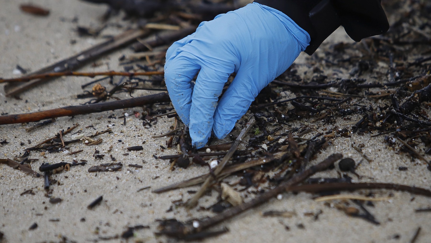 Un voluntario recoge pellets en la playa de Samil en Vigo (Foto: Europa Press)