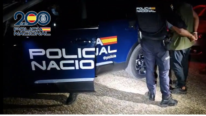 Un policía nacional traslada a uno de los detenidos hasta el vehículo.