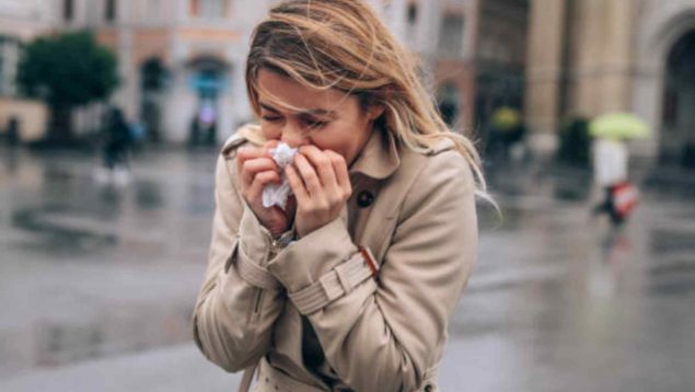 Mujer estornudando en la calle