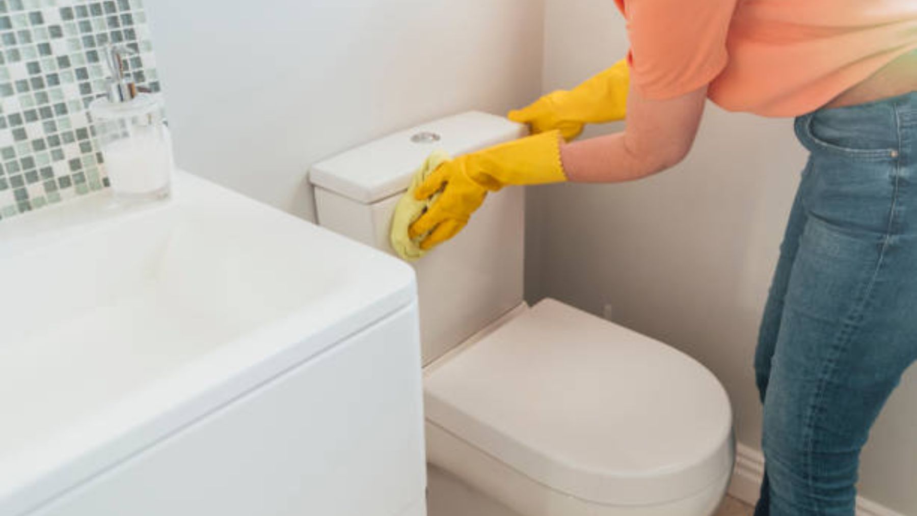 Mujer limpiando inodoro en el baño.