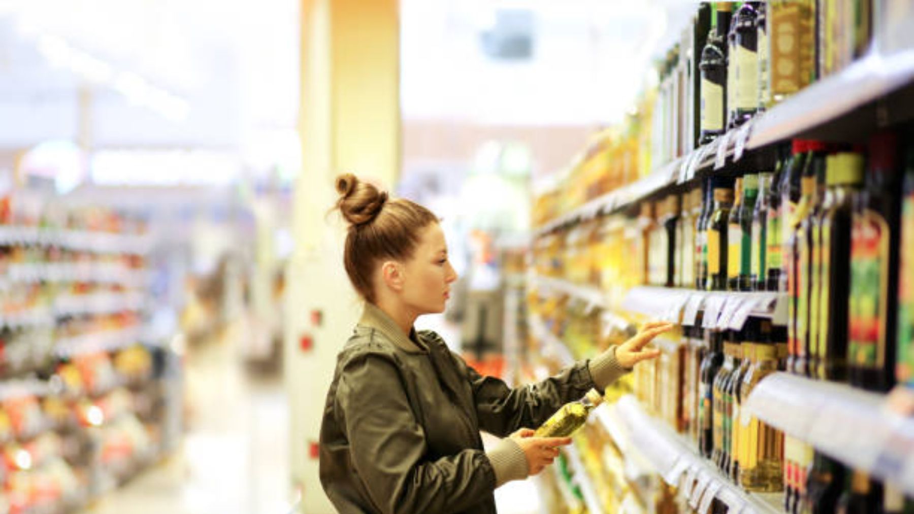 Joven eligiendo aceite en un supermercado.