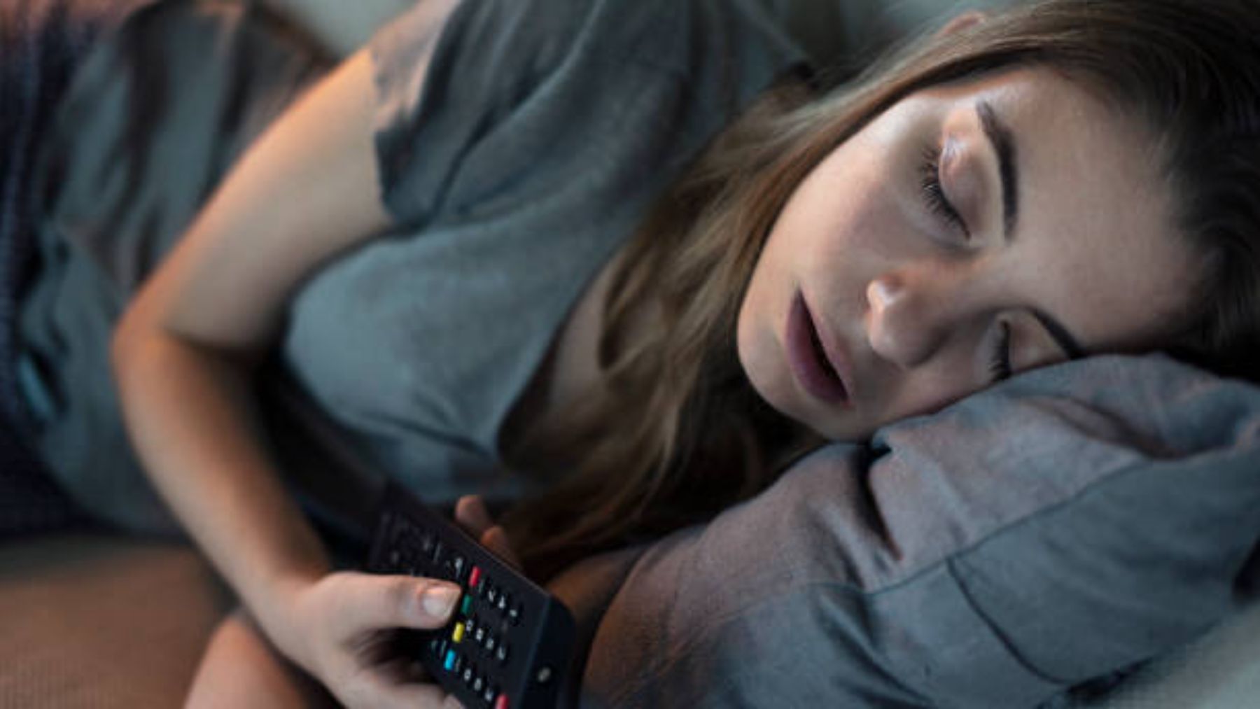 Mujer durmiendo con mando de la televisión.