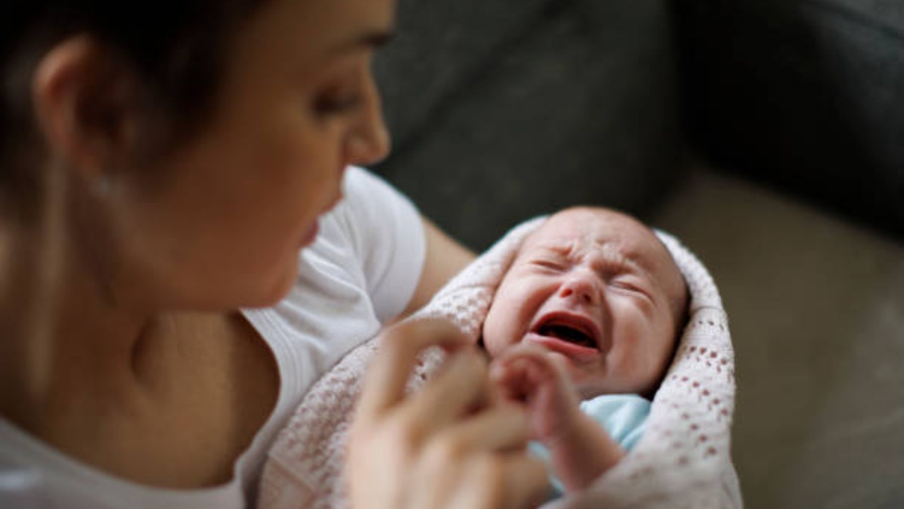 Mujer sujeta un bebé llorando.