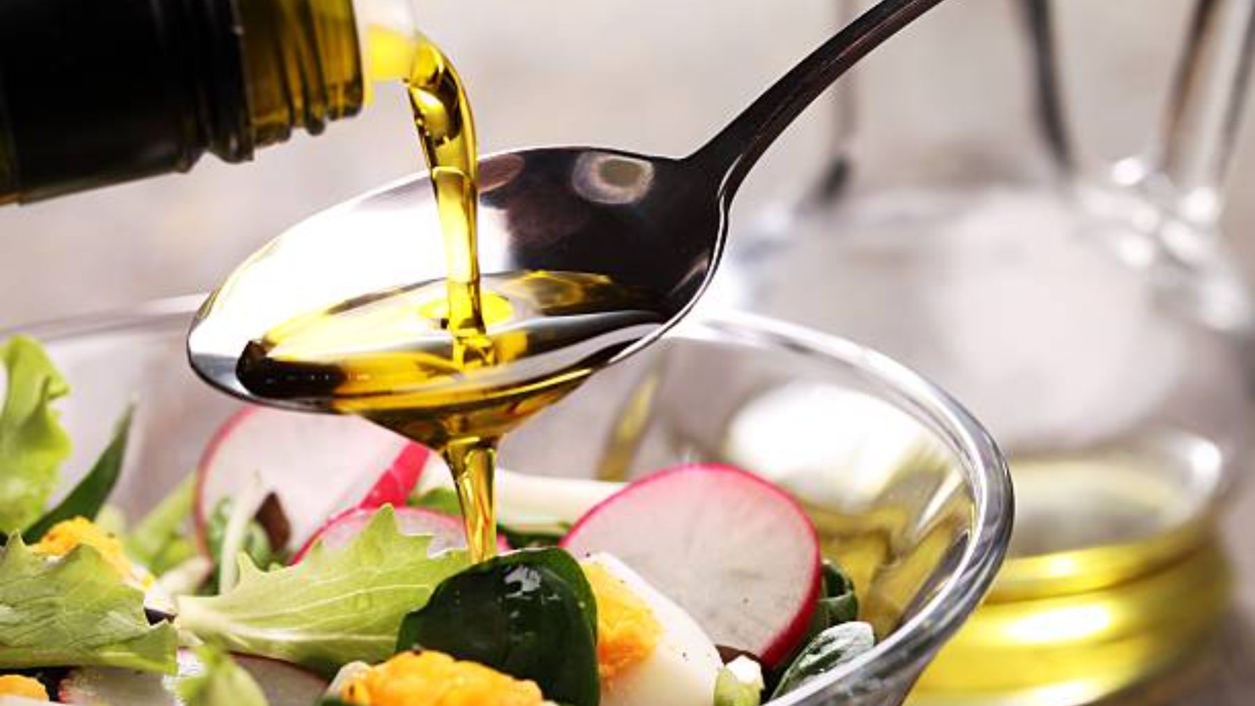 Cuchara con aceite de oliva sobre una ensalada.