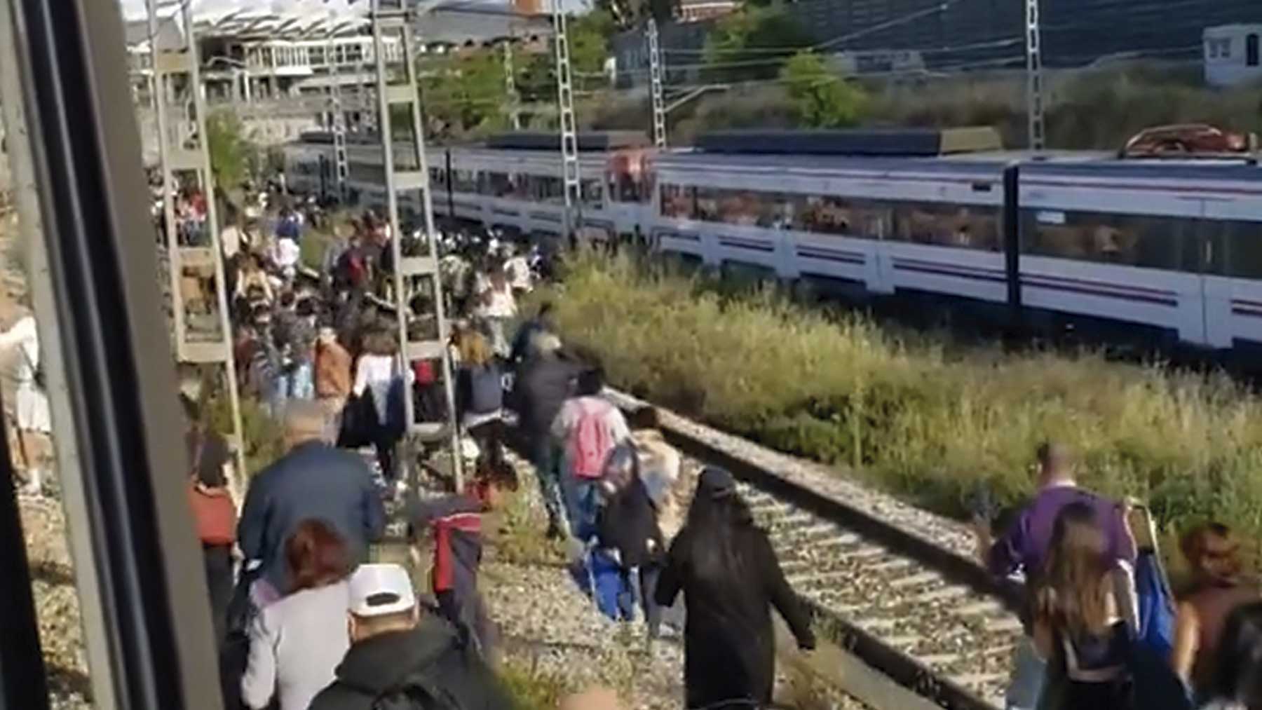 Cientos de pasajeros caminando por las vías.