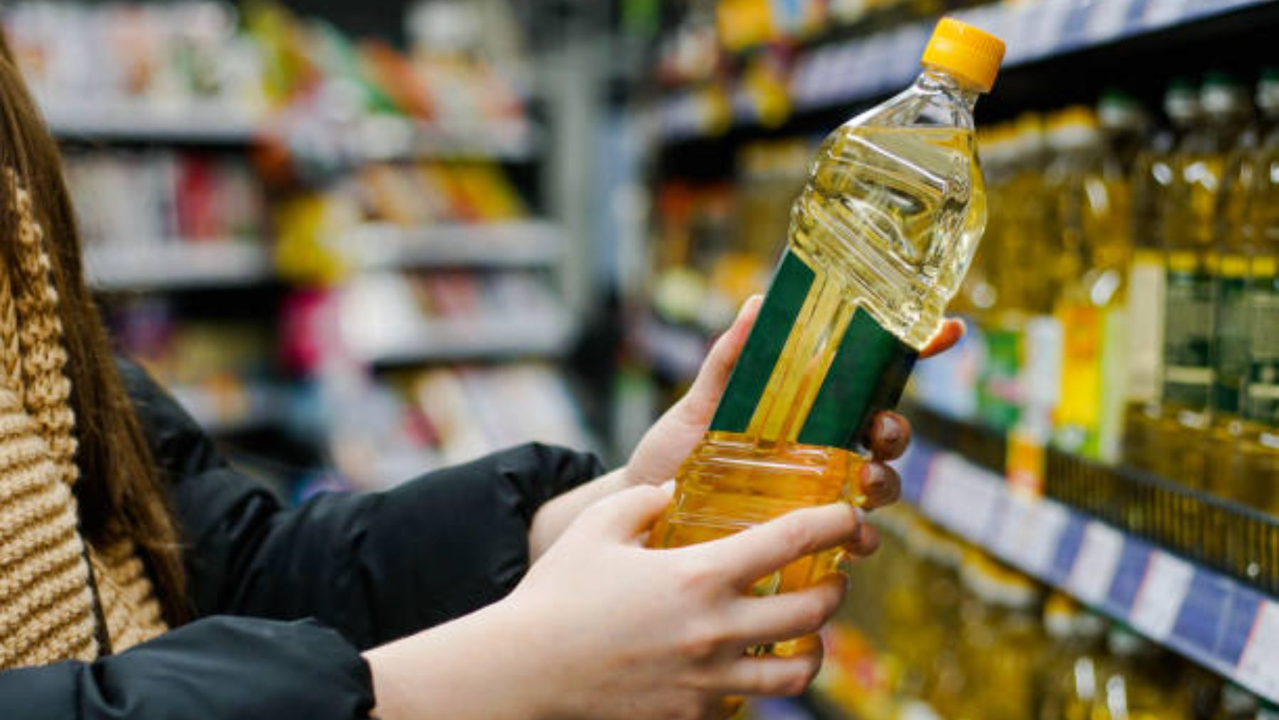 Mujer sujeta botella de aceite en un supermercado.