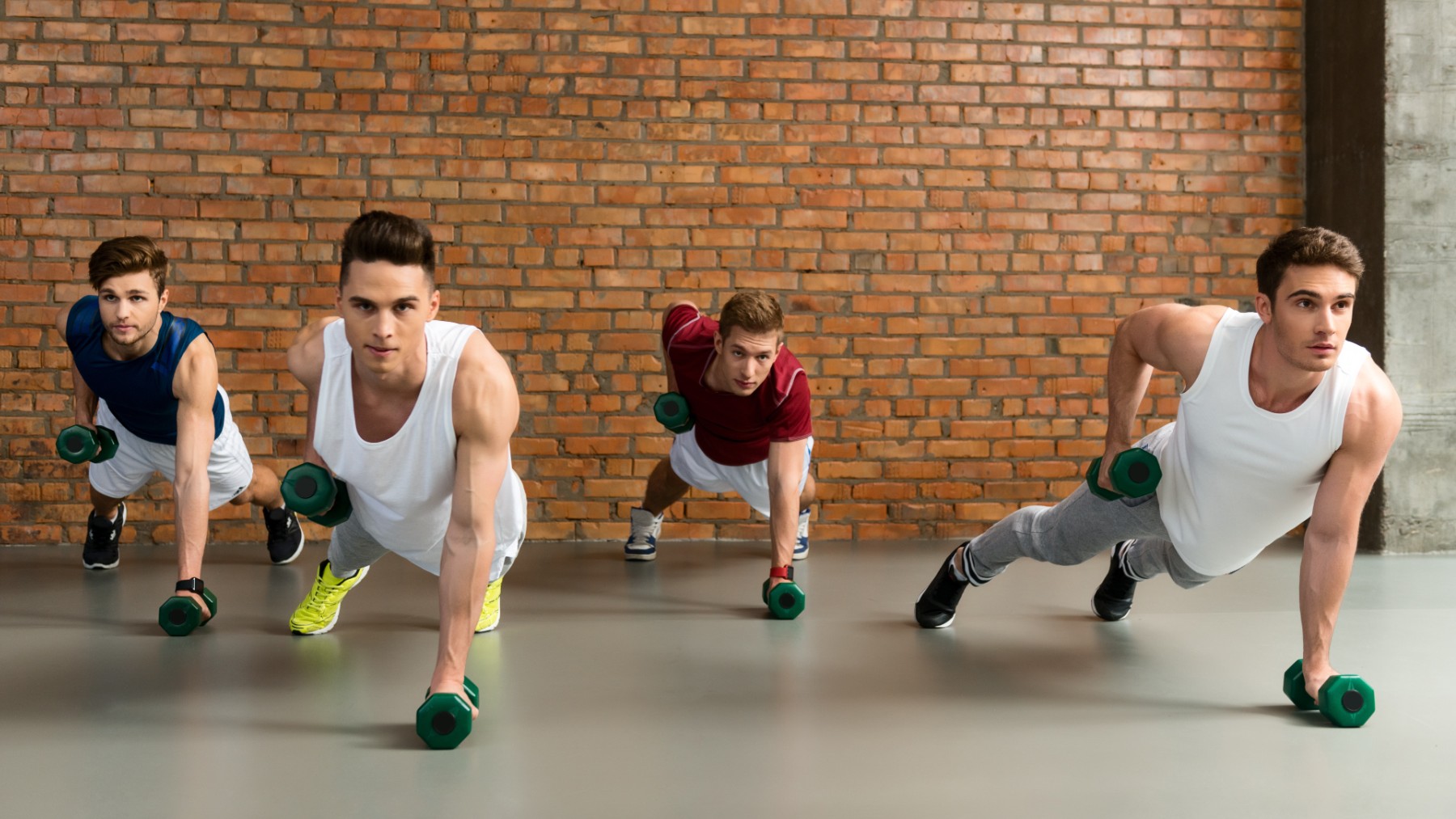 Varios jóvenes realizando deporte con pesas.
