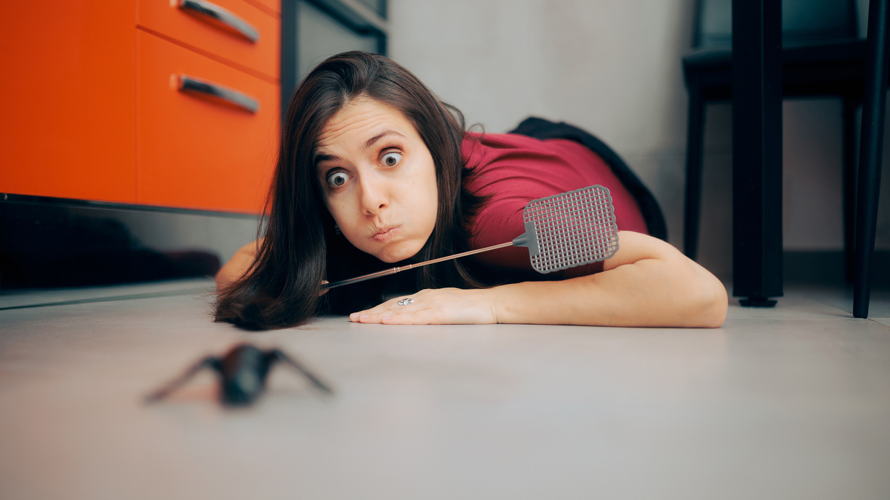 Woman Following a Big Insect on the Kitchen Floor