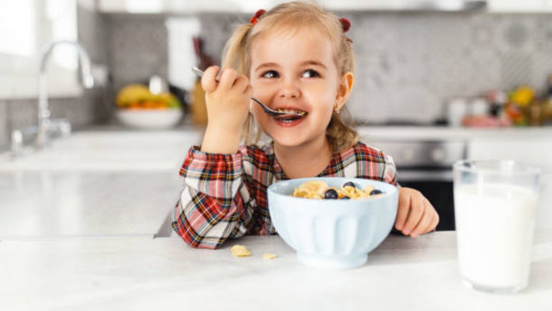 Niña sonriente desayunando cereales.