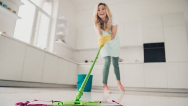 Mujer limpiando su casa con una mopa en el suelo.