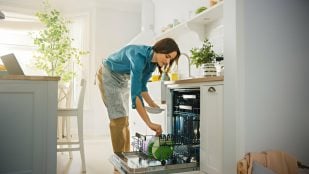 Mujer llenando el l lavavajillas en su cocina