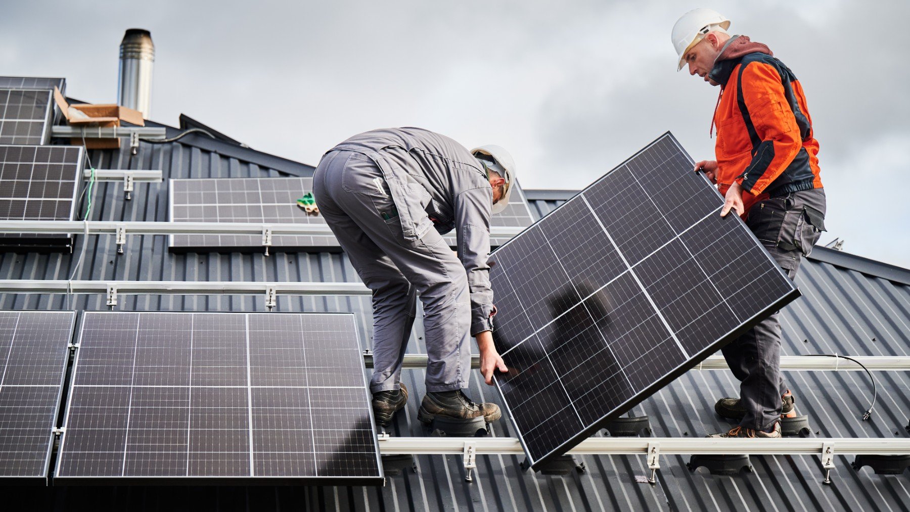 Operarios instalando el sistema de paneles solares en el techo de una casa
