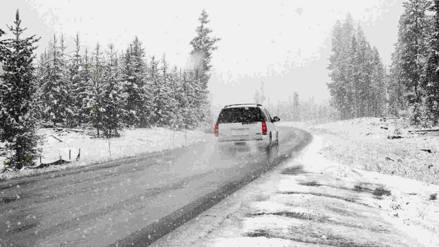 Carretera con nieve y un vehículo circulando.