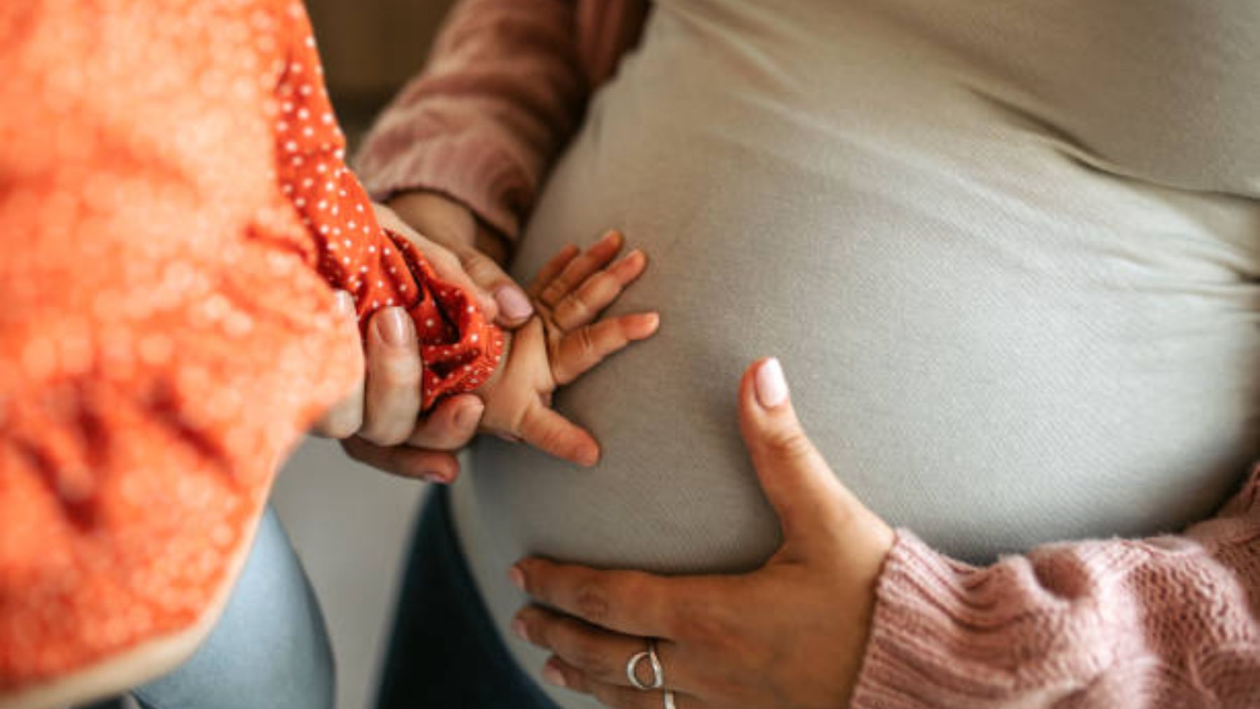 Mano de un niño toca barriga de embarazada.